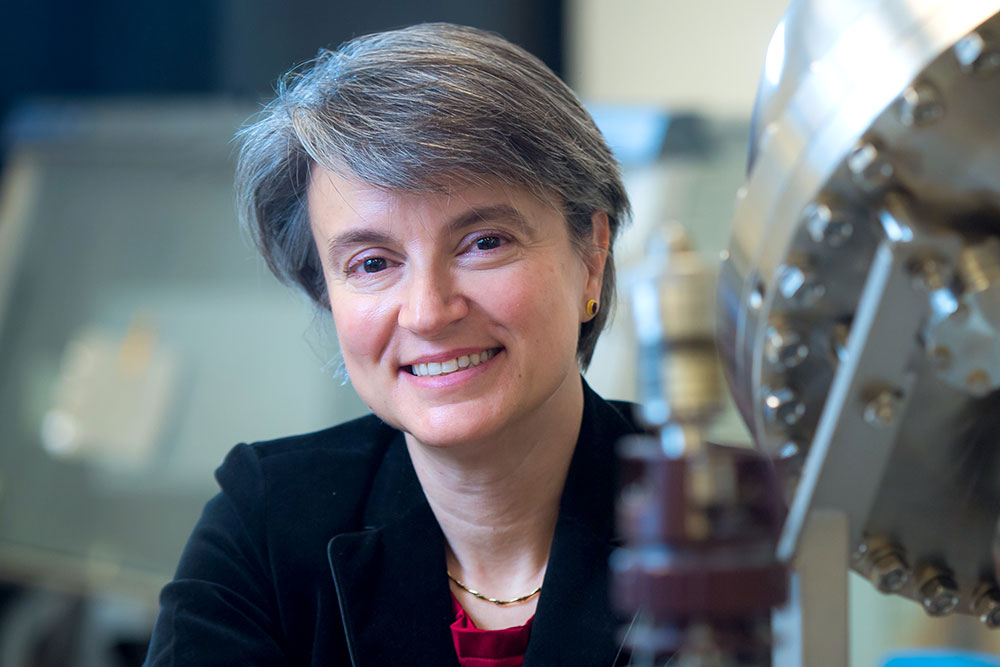 Female faculty member in front of lab equipment and instrumentation, MIT