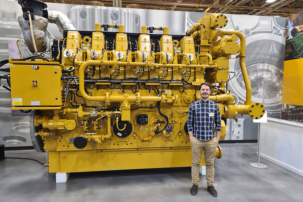 male student standing in front of machinery, MIT