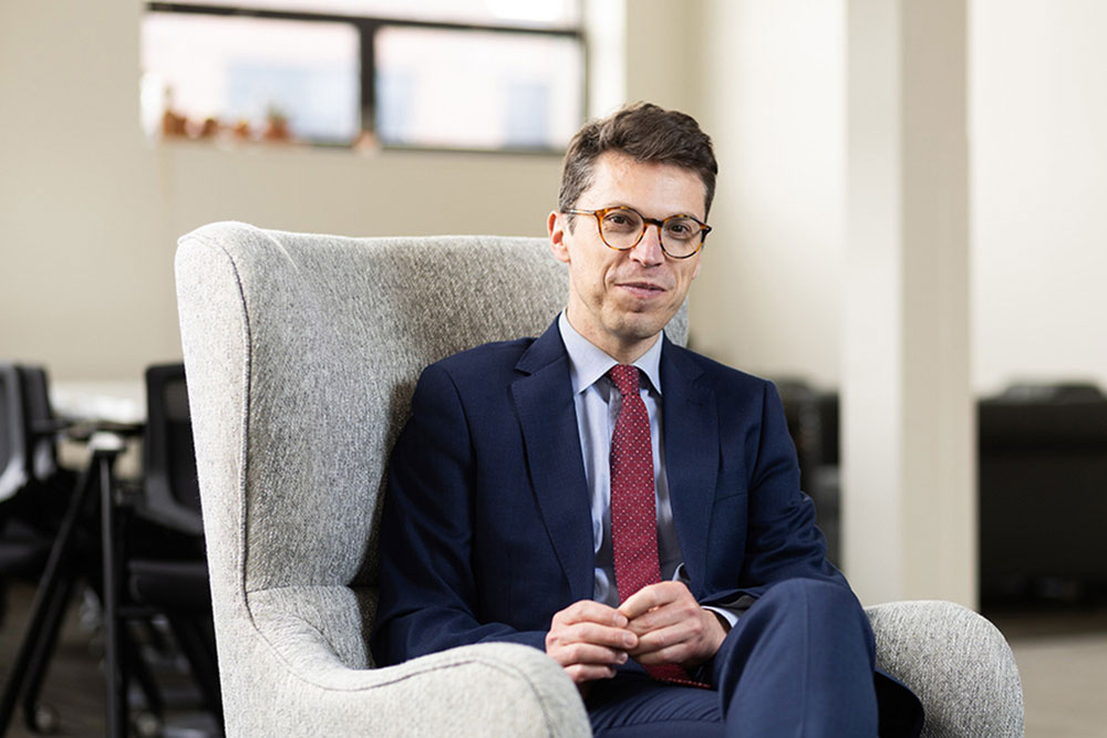 Photo of Nuno Loureiro seated indoors on a white lounge chair