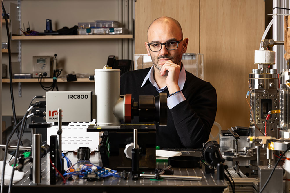 Faculty member Matteo Bucci seated at a lab bench with instruments, MIT